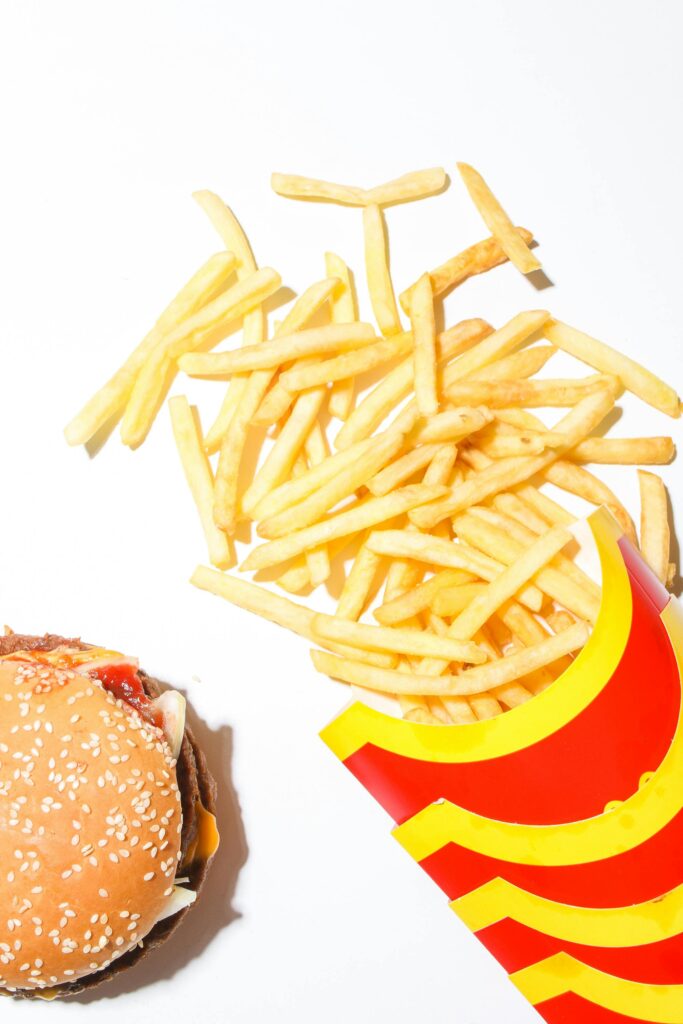 Close-up of crispy french fries and a juicy burger on a white background.