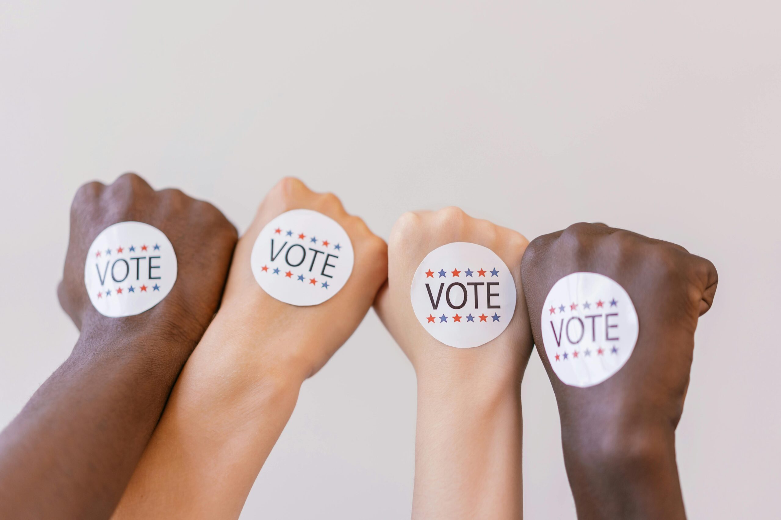 Close-up of diverse hands showing unity with vote stickers emphasizing democracy.