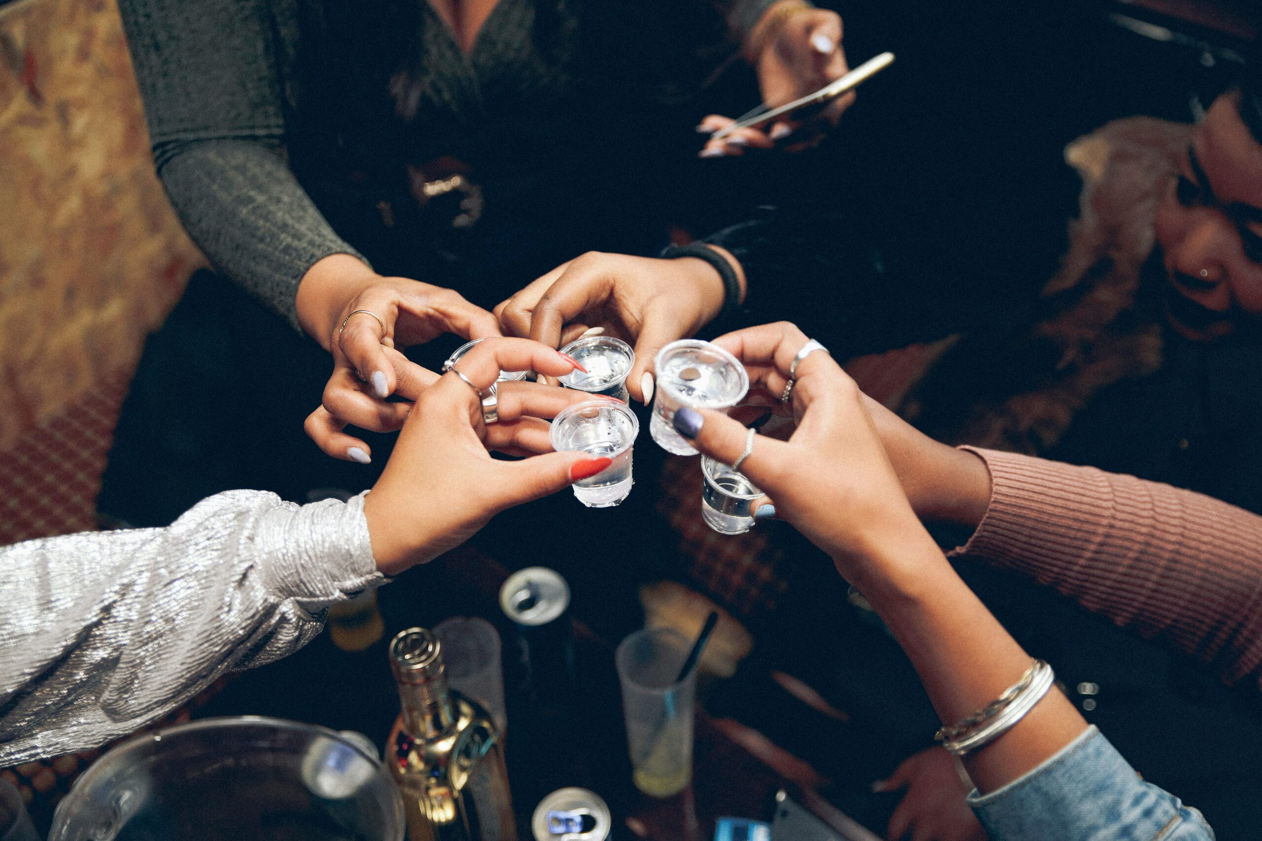 A lively gathering with friends clinking shot glasses, celebrating joy and camaraderie indoors.