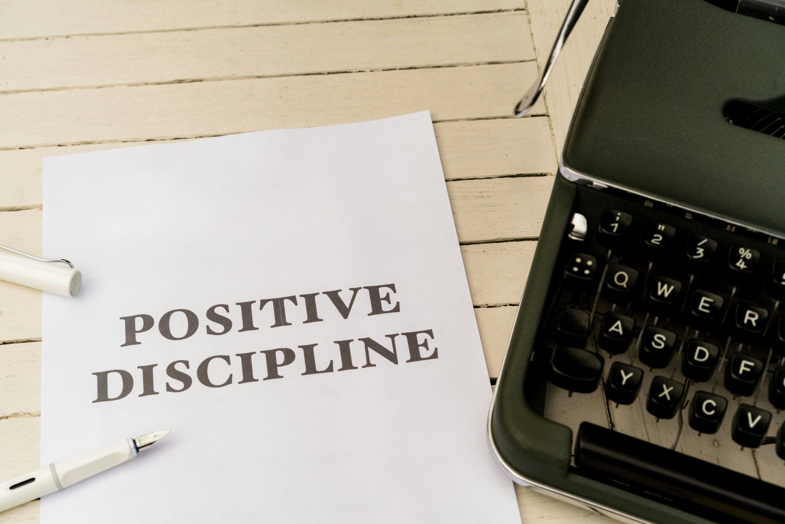 Vintage typewriter next to a paper with 'Positive Discipline' text, symbolizing communication and education.