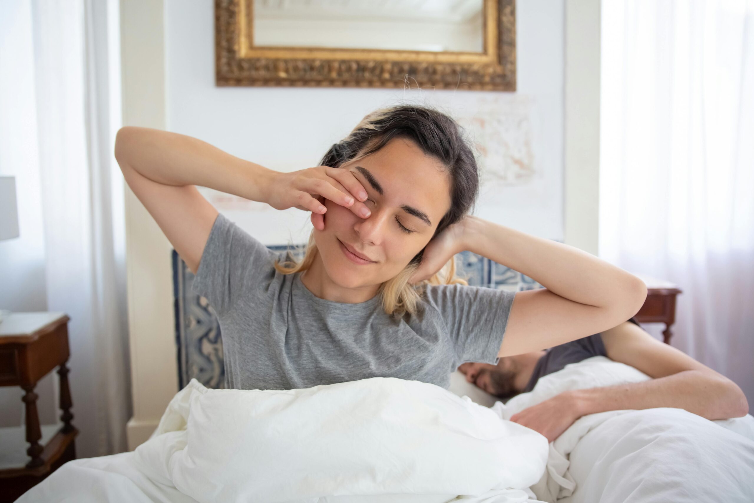 Young woman waking up with a morning stretch, captured indoors with natural light.