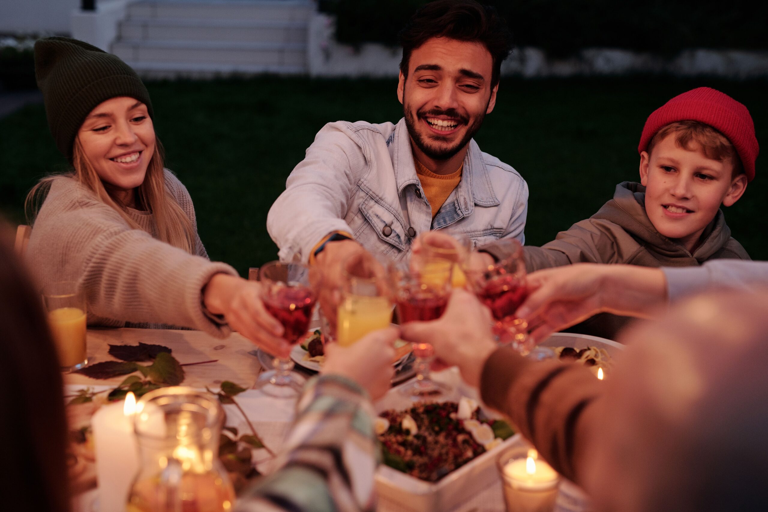Happy group enjoying candlelit dinner with cheers and smiles outdoors.